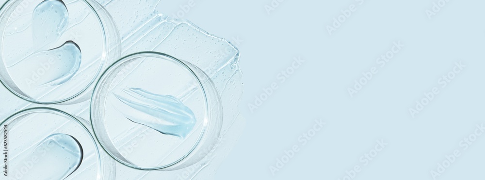 Petri dishes and drops and ointments of transparent gel or serum on a blue background. Banner with empty space for advertising. Petri dishes and drops and ointments of transparent gel or serum on a blue background. Banner with empty space for advertising.