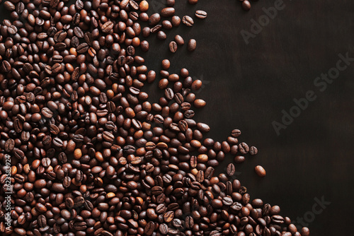 Roasted coffee beans on a wooden dark table  top view. Background of fragrant brown coffee beans scattered over the surface. copy space. Place for text