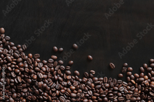 Roasted coffee beans on a wooden dark table, top view. Background of fragrant brown coffee beans scattered over the surface. copy space. Place for text