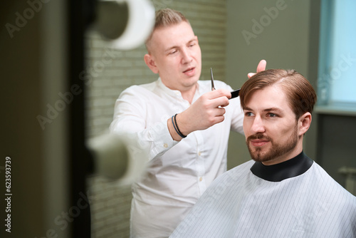 Young male hairdresser working in modern room