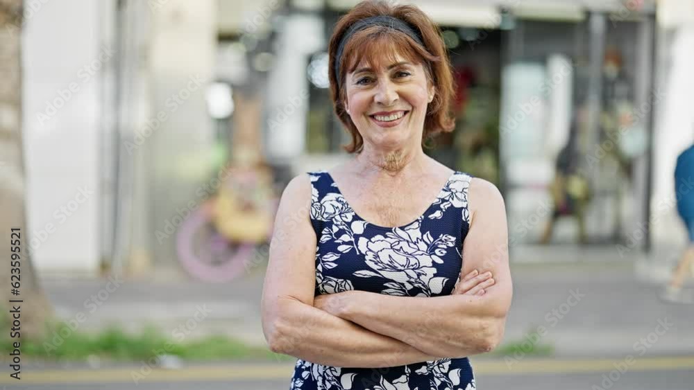 Middle age woman smiling confident standing with arms crossed gesture at street