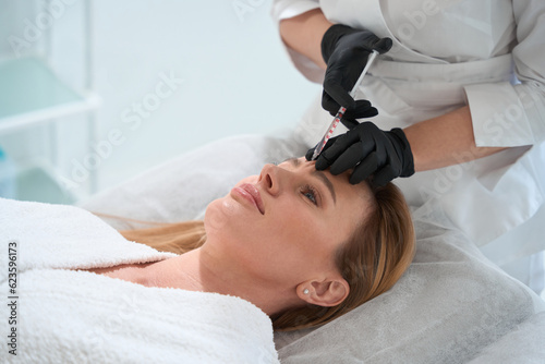 Blonde woman on injection procedure in aesthetic medicine clinic