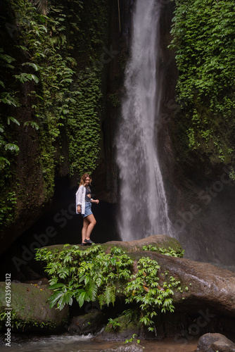 Waterfall in tropical jungle and alone woman tourist. Leke Leke waterfall in Bali, Indonesia.