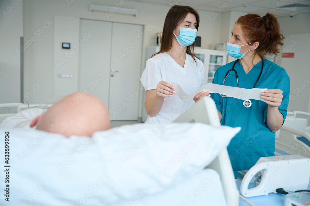 Therapists speaking near patient bed in the intensive care unit Therapists speaking near patient bed in the intensive care unit