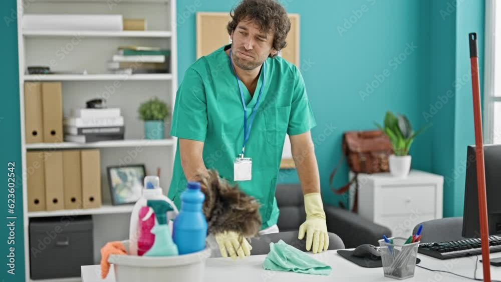 Young hispanic man cleaning table with a cloth stressed at office