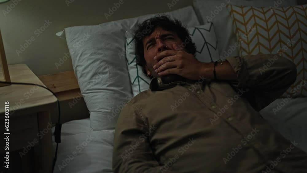 Young hispanic man lying on bed tired turning light off to sleep at bedroom Young hispanic man lying on bed tired turning light off to sleep at bedroom