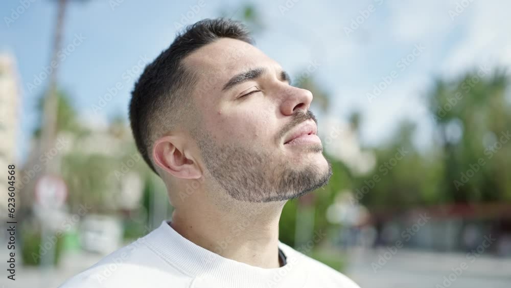 Young hispanic man breathing with closed eyes at street Young hispanic man breathing with closed eyes at street