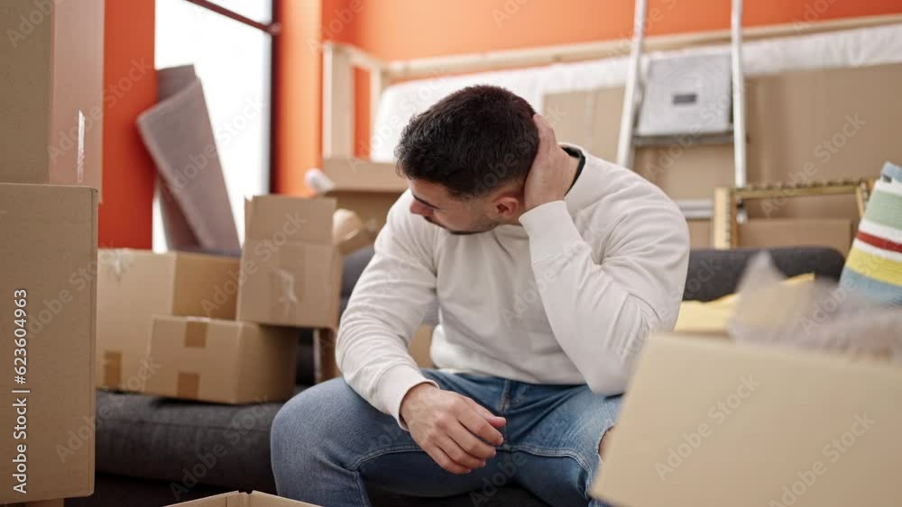 Young hispanic man stressed sitting on sofa at new home Young hispanic man stressed sitting on sofa at new home