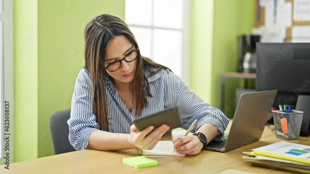 Young beautiful hispanic woman business worker using touchpad taking notes at office Young beautiful hispanic woman business worker using touchpad taking notes at office
