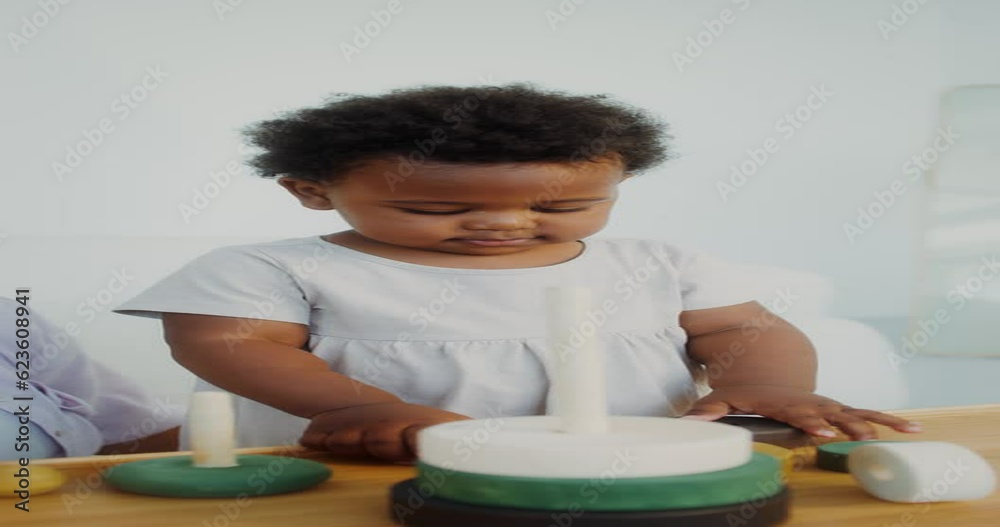 Mom and daughter of African-American appearance play with wooden toys sitting near the table in a white room Mom and daughter of African-American appearance play with wooden toys sitting near the table in a white room