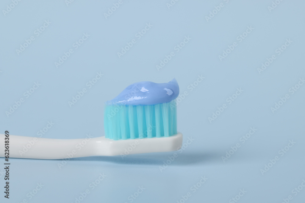 Plastic toothbrush with paste on light blue background, closeup Plastic toothbrush with paste on light blue background, closeup