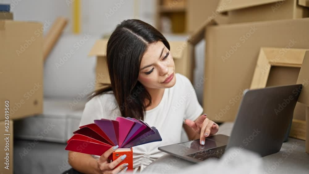 Young caucasian woman using laptop choosing color at new home Young caucasian woman using laptop choosing color at new home