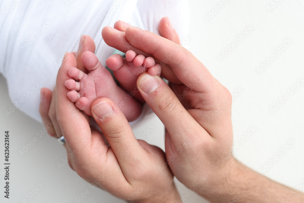 The palms of the father, the mother are holding the foot of the newborn baby on white background. Feet of the newborn on the palms of the parents. Photography of a child's toes, heels and feet.