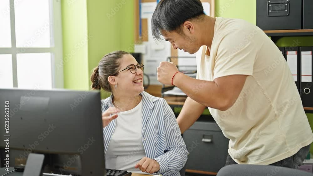 Man and woman business workers using computer working high five at office Man and woman business workers using computer working high five at office