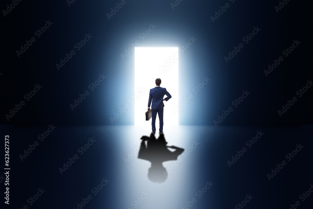 Businessman entering backlit door in escape concept Businessman entering backlit door in escape concept