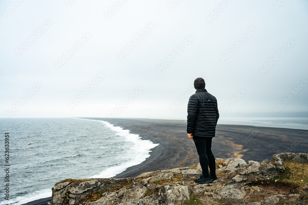 Man looking out at the black sand of Hvalnes Beach