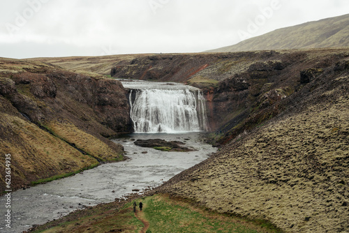 View of the beautiful Thorufoss      rufoss  waterfall in Iceland with hikers walking to falls.