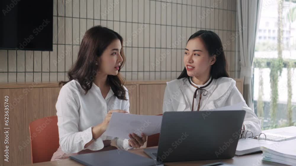 Two business women sit at desk discuss project details, diverse female colleagues met in office, share opinion, working on collaborative task, sales manager makes commercial offer to company client Two business women sit at desk discuss project details, diverse female colleagues met in office, share opinion, working on collaborative task, sales manager makes commercial offer to company client