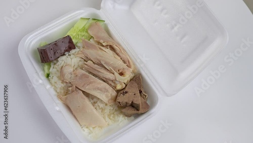 Steamed rice topped with chicken in foam box roatating. photo