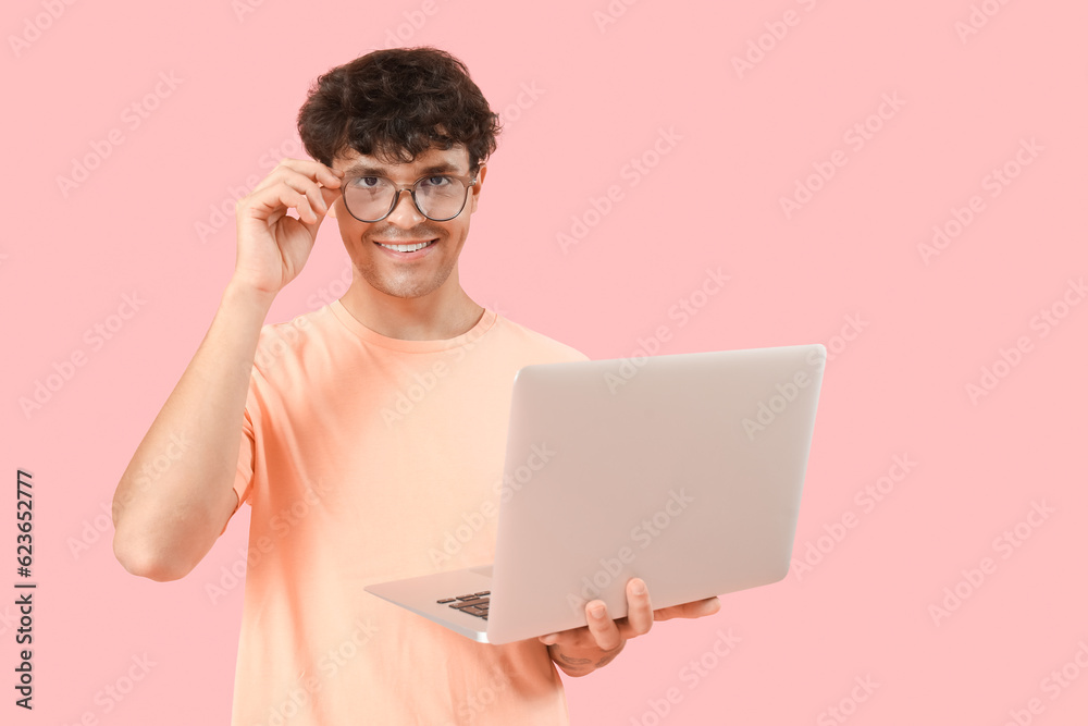 Male programmer working with computer on pink background Male programmer working with computer on pink background