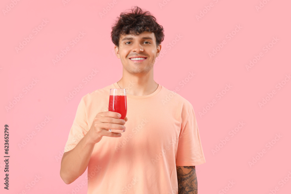 Young man with glass of red juice on pink background Young man with glass of red juice on pink background
