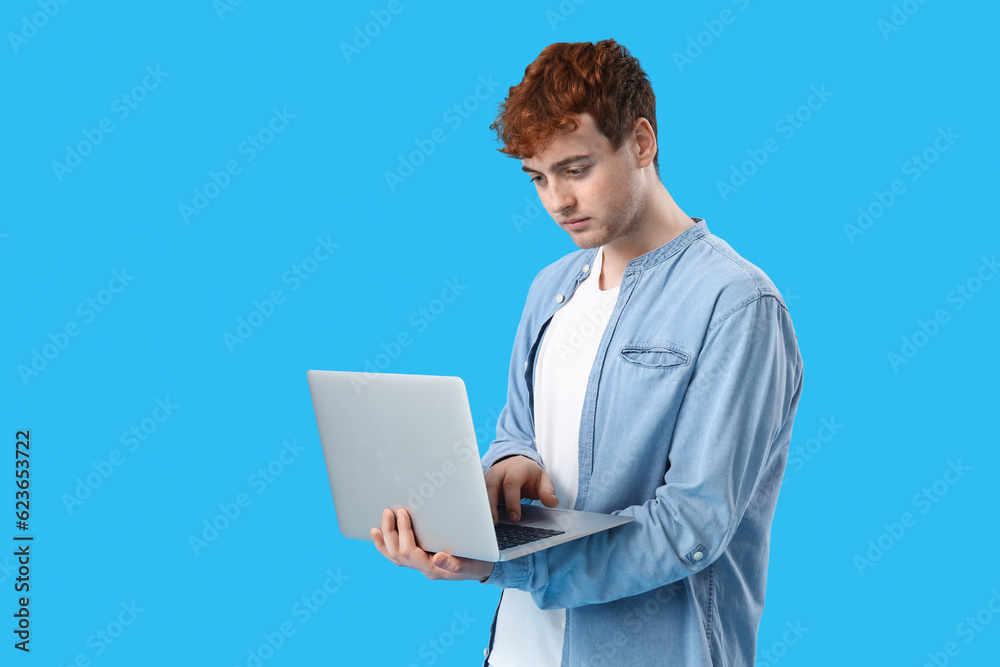 Male programmer working with laptop on blue background Male programmer working with laptop on blue background