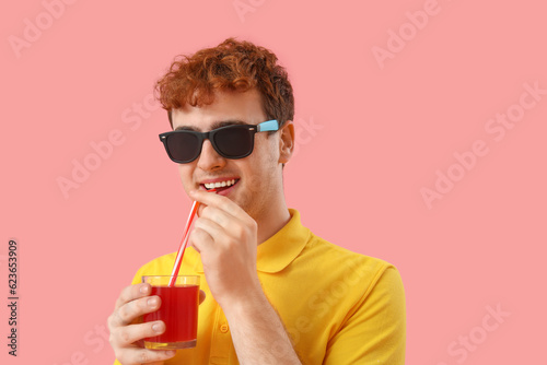 Young man drinking red juic...