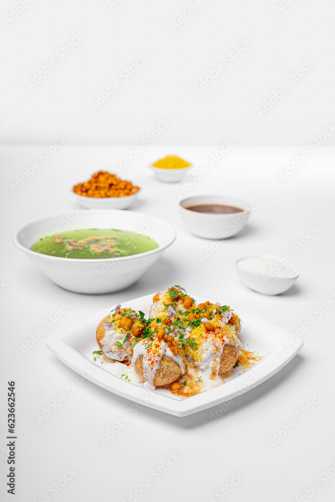 dahi puri or dahipuri a very spicy punjabi chat item on white plate with chutney and chilly water bowls, styling and garnished group shot