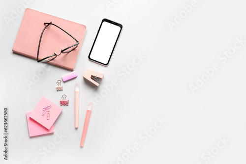 Different stationery with mobile phone and eyeglasses on grey background