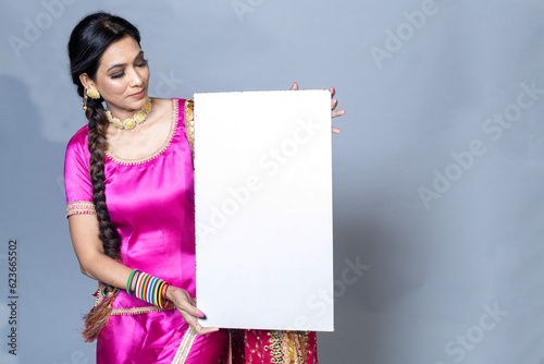 A Punjabi woman with sign board looking towards the camera studio shot photo