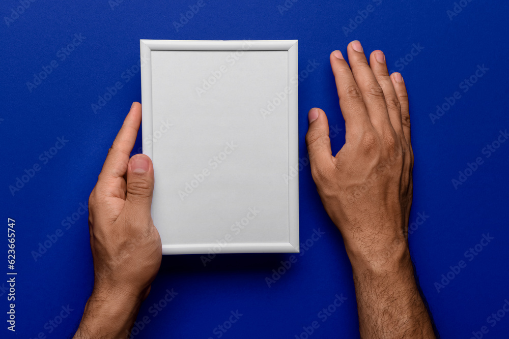 Man holding blank photo frame on blue background Man holding blank photo frame on blue background