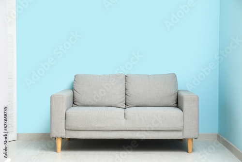 Cozy grey sofa near blue wall