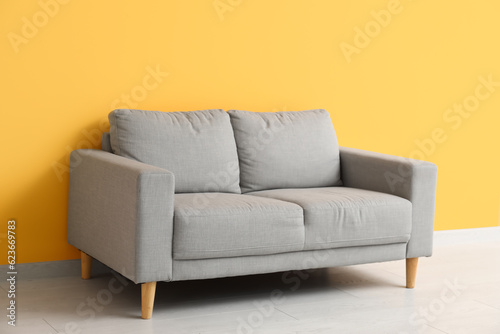 Cozy grey sofa near orange wall © Pixel-Shot