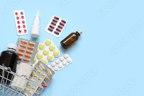 Mini shopping basket with different medicines on blue background