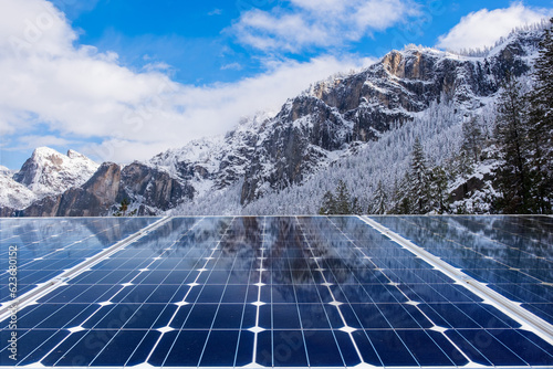 Solar panels with mountain landscape at sunset. Green energy concept.