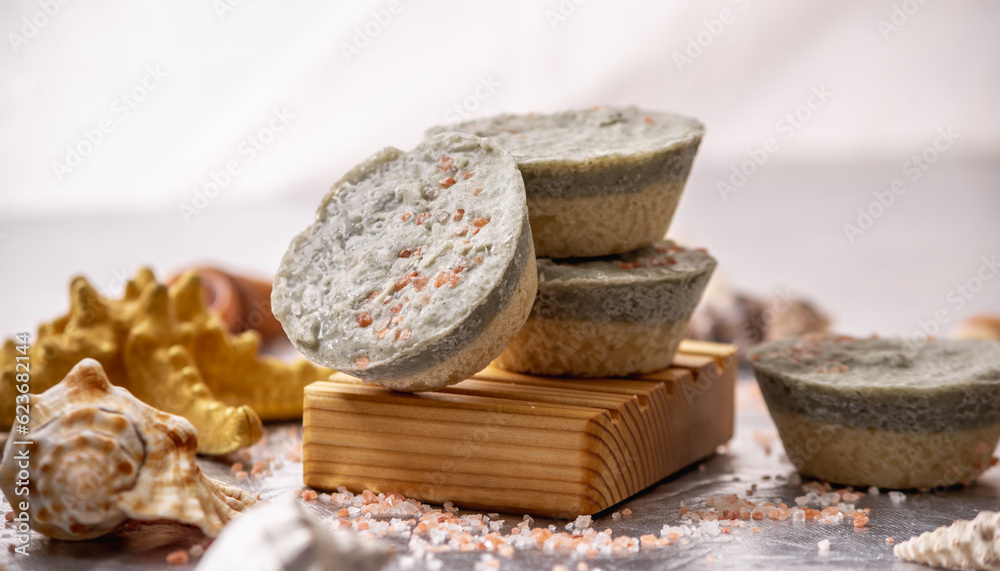 Natural soap with sea salt on a wooden soap dish, shells and a starfish. Organic summer soap, immersing in the marine atmosphere Natural soap with sea salt on a wooden soap dish, shells and a starfish. Organic summer soap, immersing in the marine atmosphere