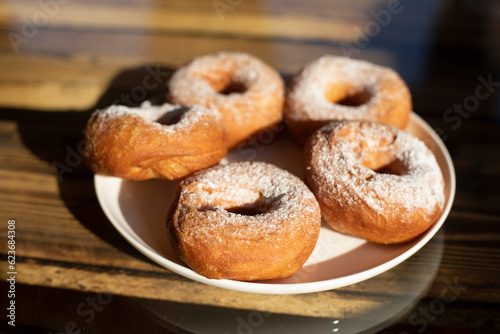 Donuts with powdered sugar. Delicious food in light of sun. Sweet tea.