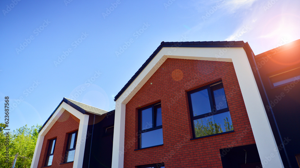 New single family houses in a new development area. Residential homes with modern facade. Terraced family homes in newly developed housing estate. The real estate market in the suburbs.