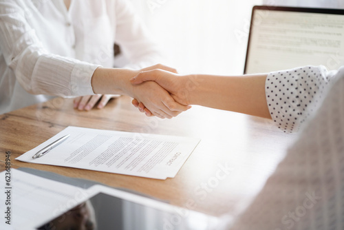 Business people shaking hands above contract papers just signed on the wooden table, close up. Lawyers at meeting. Teamwork, partnership, success concept