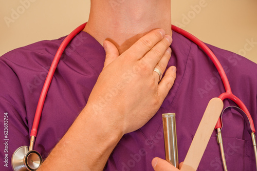 Lekarz laryngolog pokazuje badanie gardła , trzyma się za krtań 