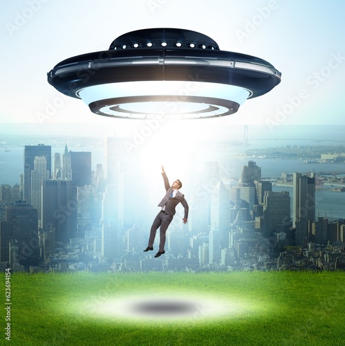 Foto Flying saucer abducting young businessman
