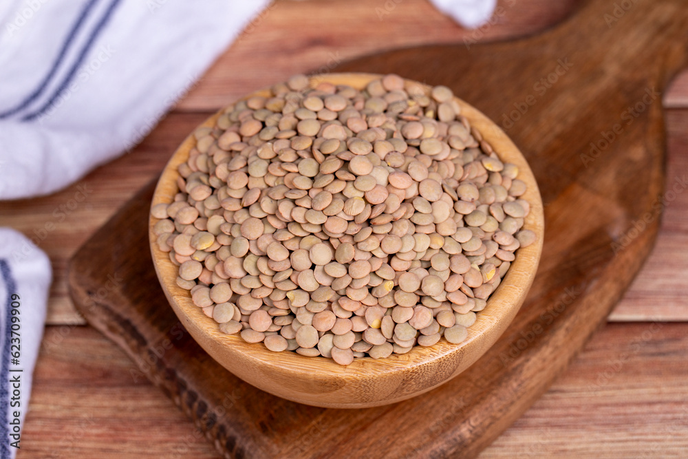 Green lentils on wood background. Raw green lentils in wooden bowl Green lentils on wood background. Raw green lentils in wooden bowl