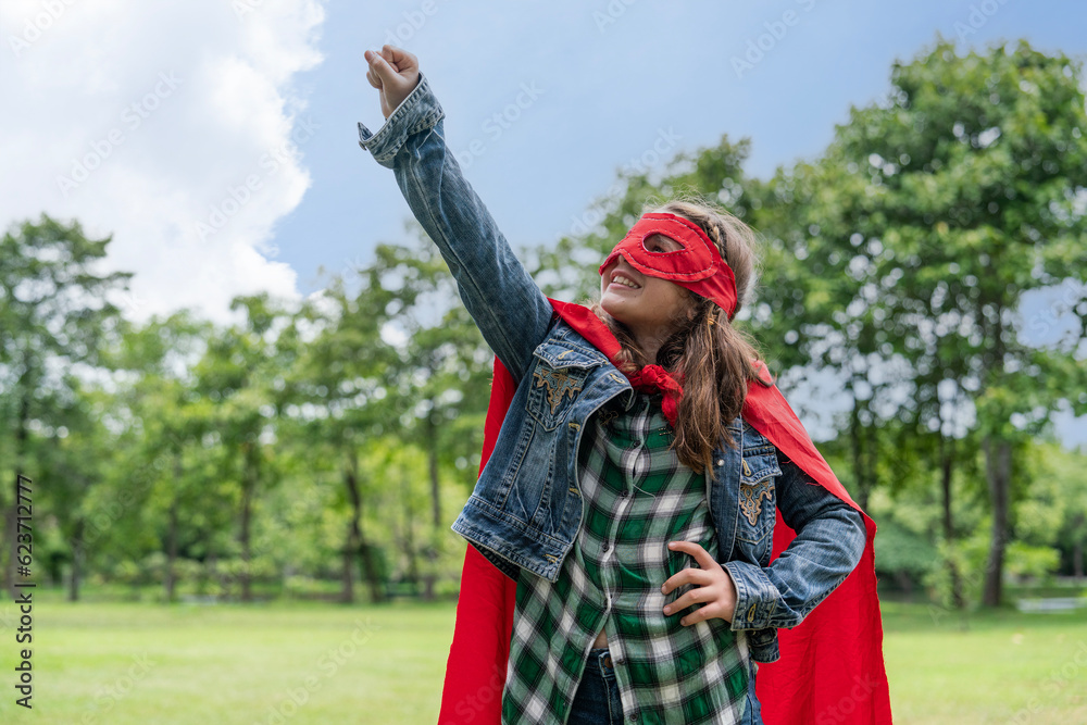 Caucasian girl having fun wearing red mask, red cape, running cross like a fly in the park. The superhero concept saves the global environment and enjoylife.
