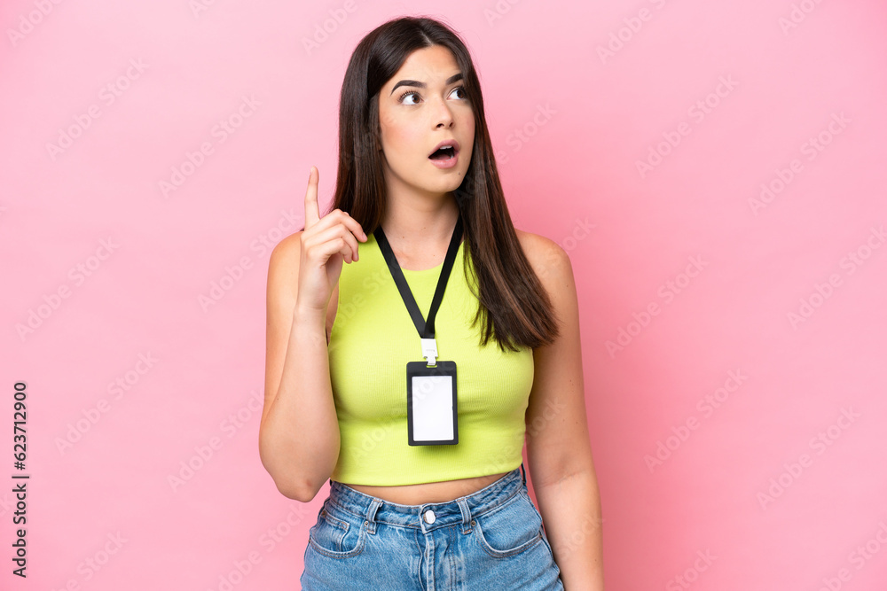 Young Brazilian woman with ID card isolated on pink background thinking an idea pointing the finger up Young Brazilian woman with ID card isolated on pink background thinking an idea pointing the finger up