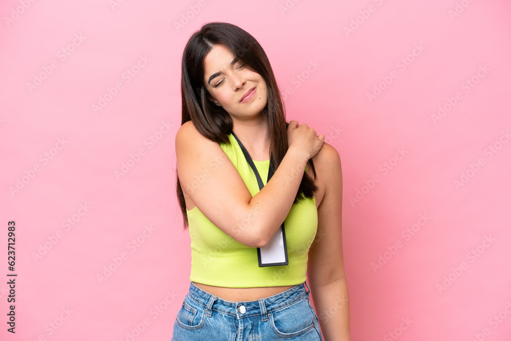 Young Brazilian woman with ID card isolated on pink background suffering from pain in shoulder for having made an effort Young Brazilian woman with ID card isolated on pink background suffering from pain in shoulder for having made an effort