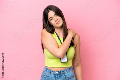 Young Brazilian woman with ID card isolated on pink background suffering from pain in shoulder for having made an effort