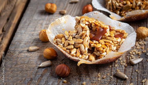 Roasted nuts and sunflower seeds in caramel and sugar on the old wooden background. Selective focus.