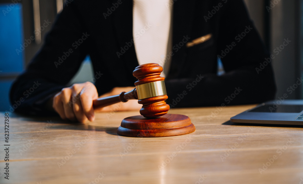 Justice and law concept.Male judge in a courtroom with the gavel, working with, computer and docking keyboard, eyeglasses, on table in morning light