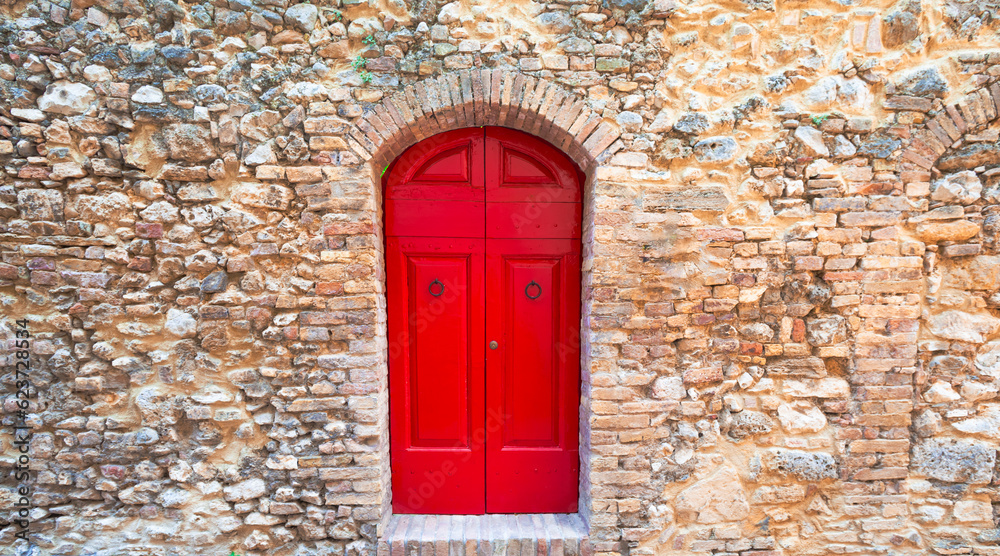 Antique wooden door, vibrant red paint, historic walls, San Gimignano, Tuscany. Antique wooden door, vibrant red paint, historic walls, San Gimignano, Tuscany.