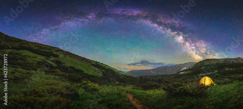 Starry panorama in the mountains with a tourist tent